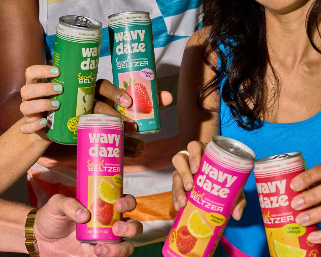 Wavy Daze saffron-infused social seltzer cans in Strawberry Basil, Raspberry Lemon, Cherry Limeade, and Crisp Apple.